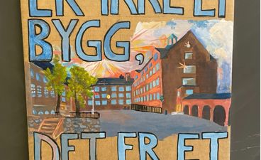 Et skilt med en bygning i bakgrunnen