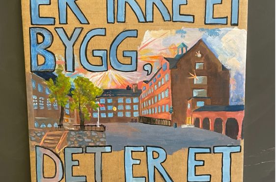 Et skilt med en bygning i bakgrunnen