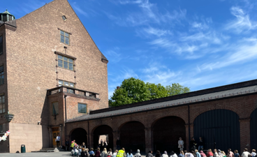 en gruppe mennesker som sitter på bakken utenfor en bygning