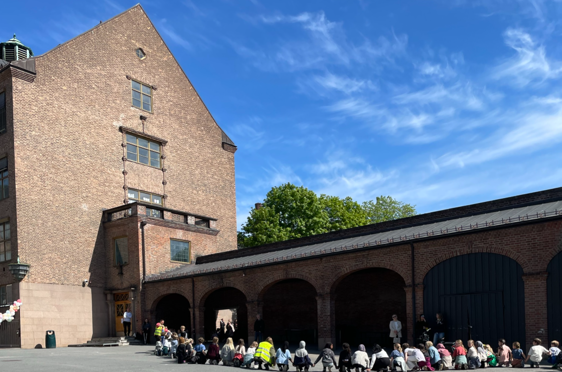 en gruppe mennesker som sitter på bakken utenfor en bygning